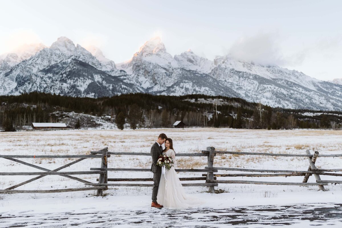 A bride and a groom in front of a snow covered field by the Grand Teton in Grand Teton National Park