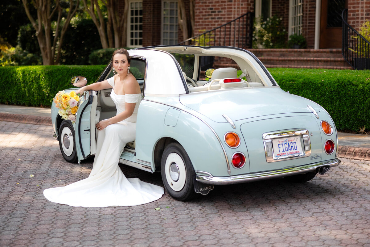 Experience the charm of a wedding day with this delightful photo of a bride sitting in a classic blue convertible, beautifully complemented by her soft vibrant citrus-colored bouquet.