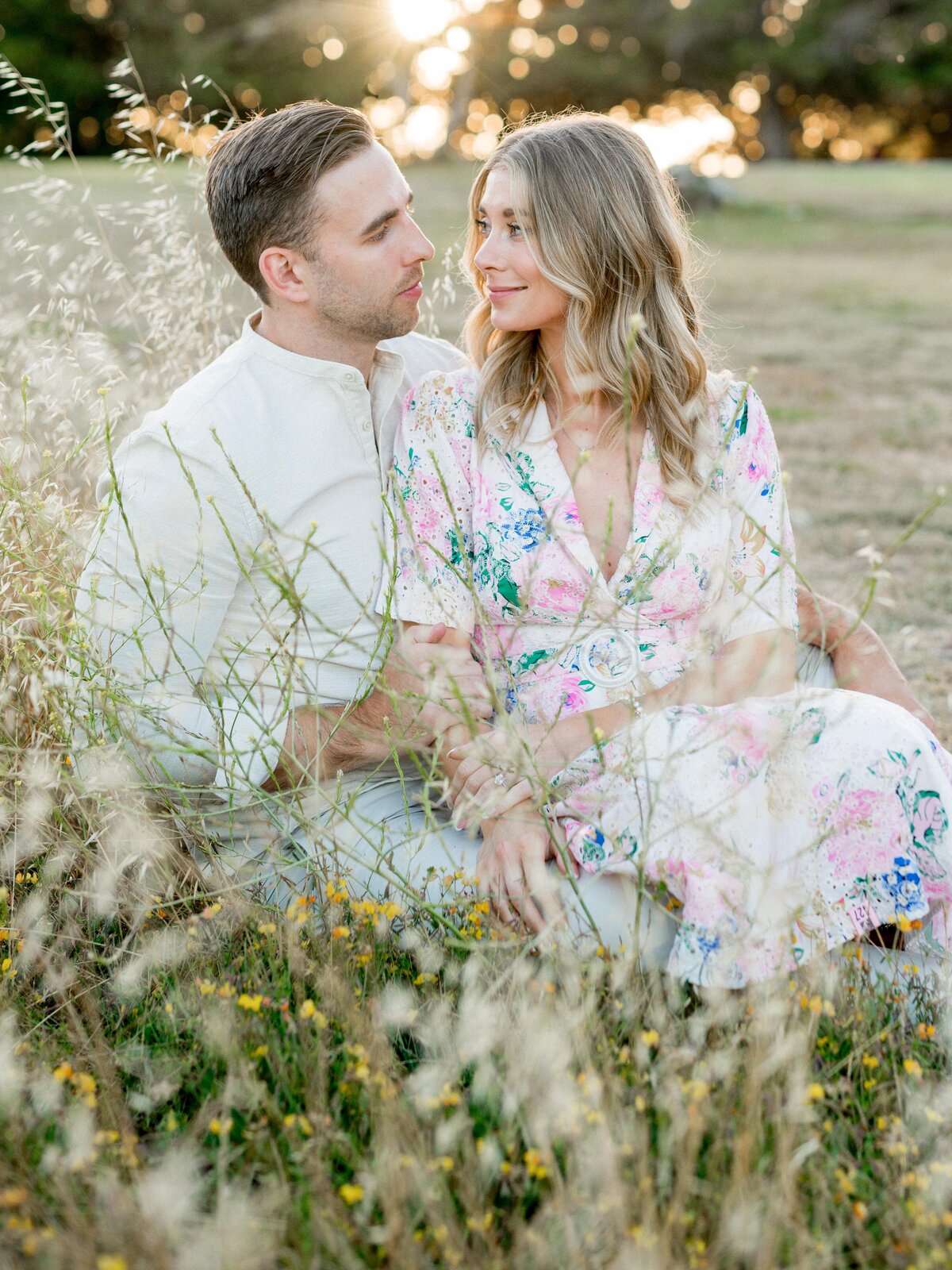 Romantic couple sitting in wildflowers during golden hour