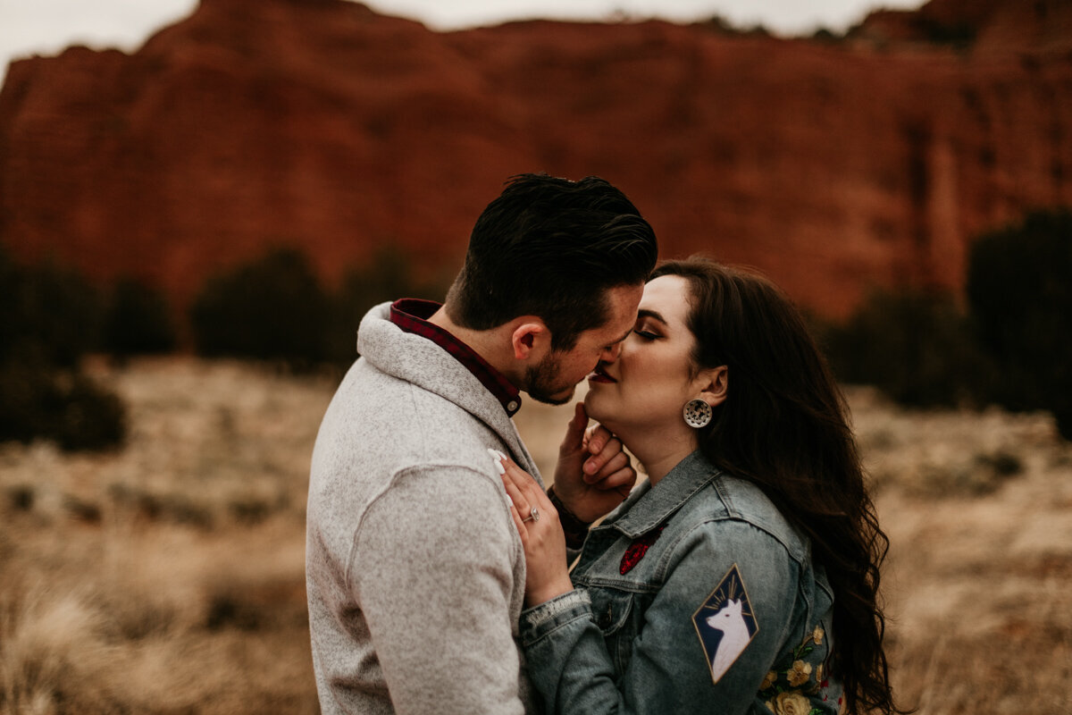 engaged couplpe about ti kiss in desert