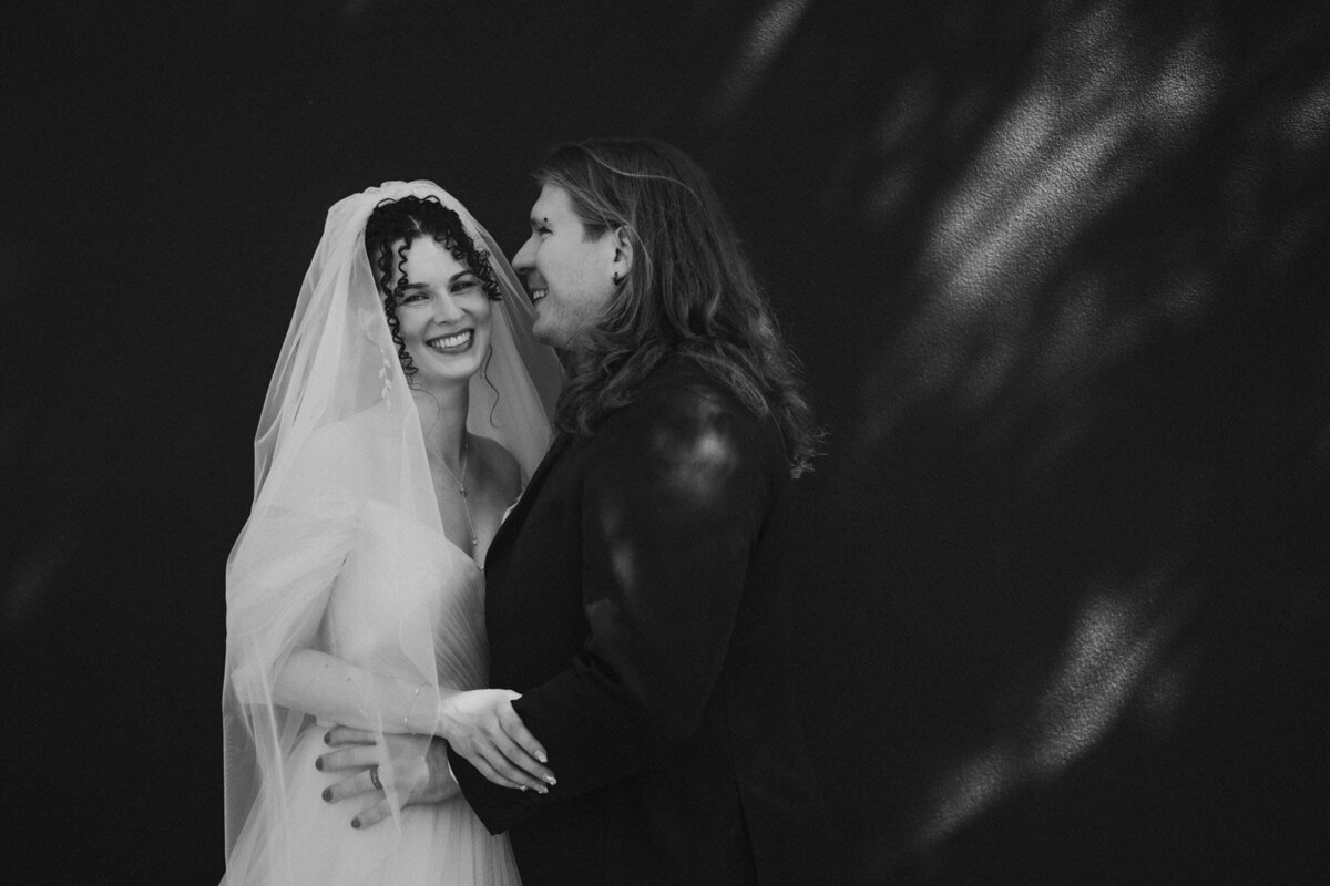 Couple smiles in black and white photo with dappled light