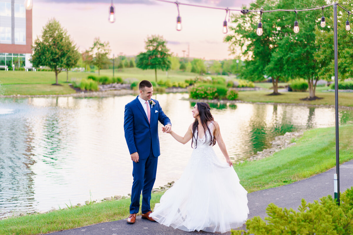 Groom twirls his bride as they look at each other by a pond outside their wedding at the Renaissance Hotel in Westerville, Ohio.