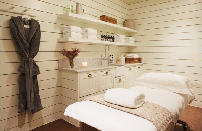Vintage inspired spa treatment room with white wood board panelled wall, cork floor and white built in millwork