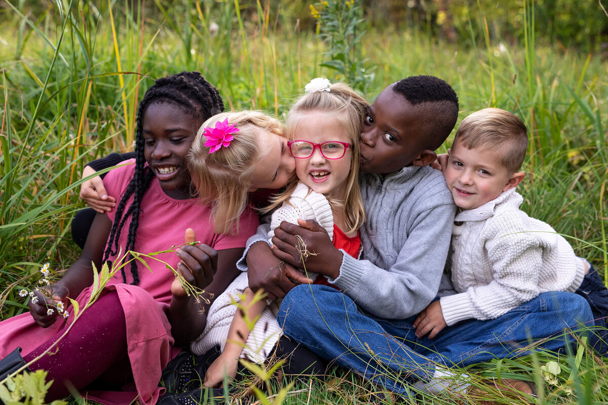 Minnesota family sits in grass at Minnehaha Creek for family photography