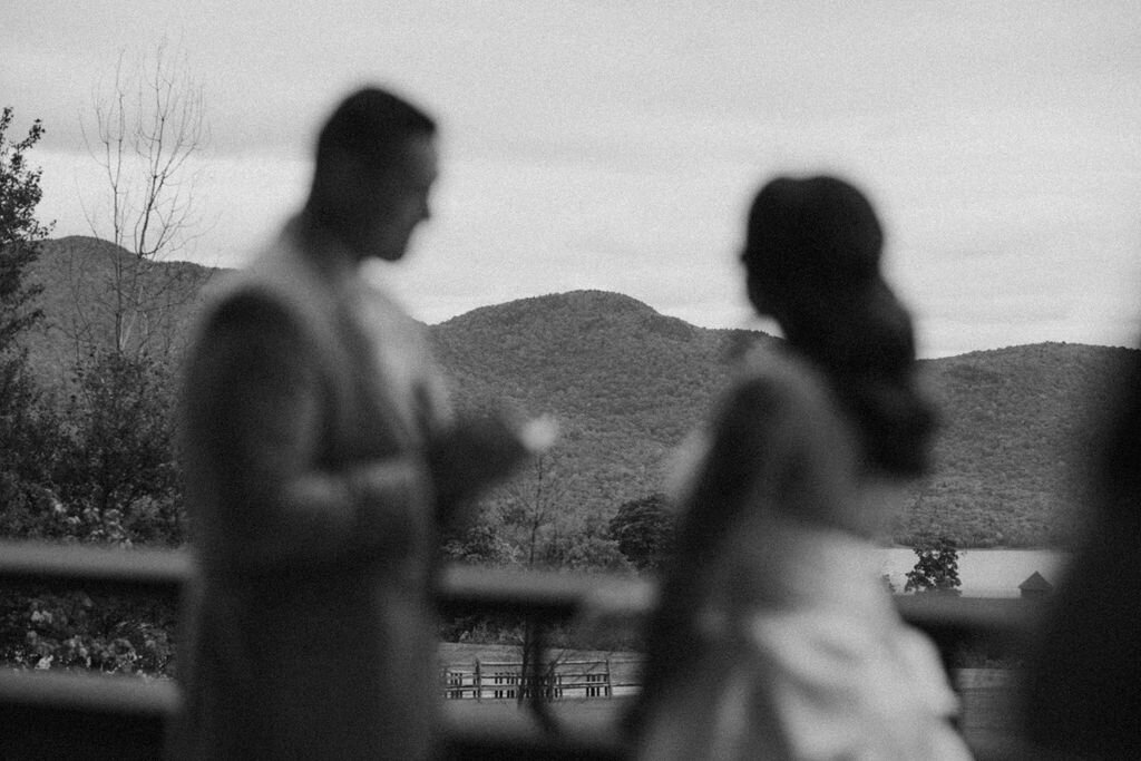 Silhouetted figures against mountain landscape in soft focus black and white.
