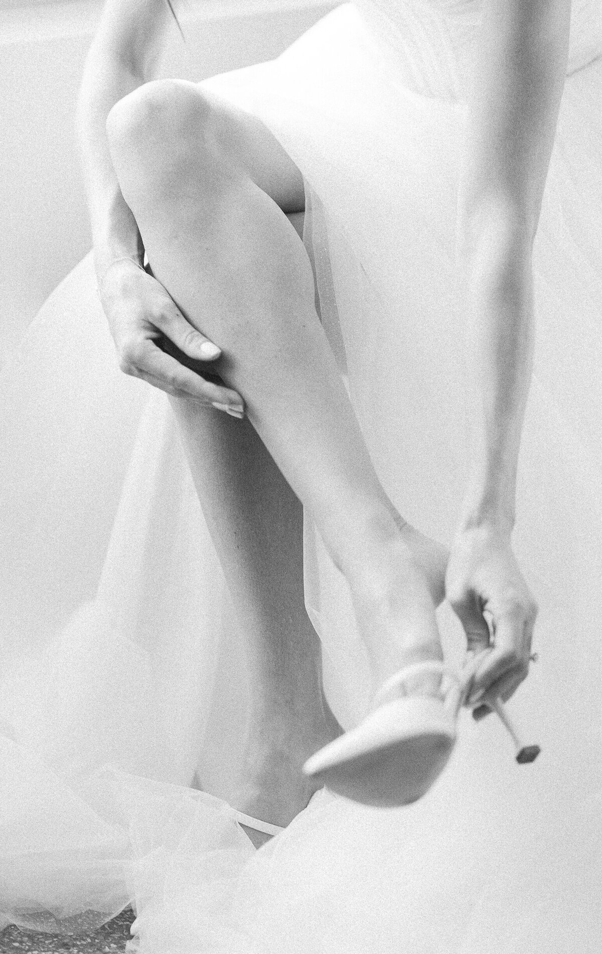 Bride putting on her shoe in black and white, taken by Claudia Amalia, Miami wedding photographer.