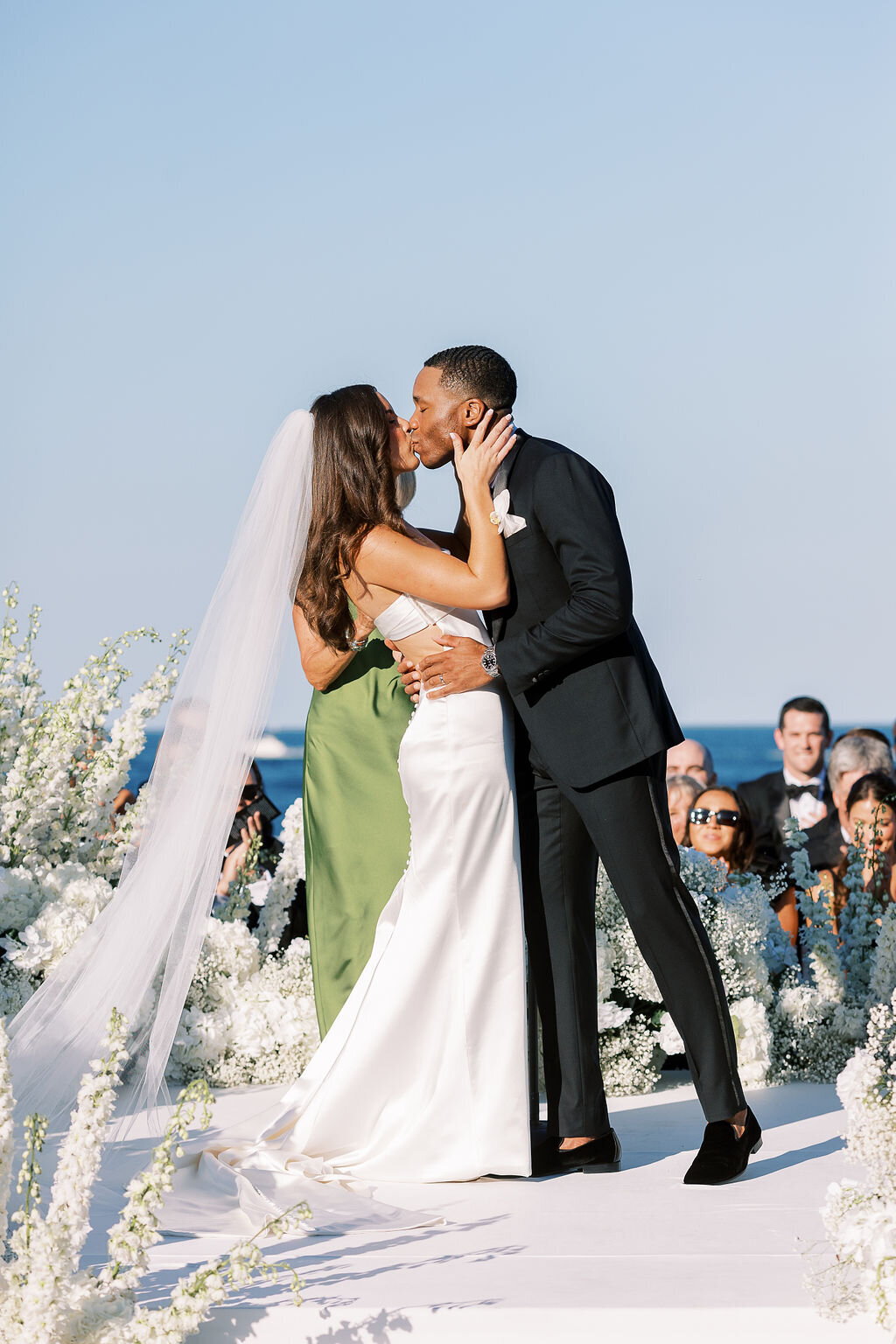 The bride and groom share a romantic kiss after being pronounced married, with Lake Michigan in the background.