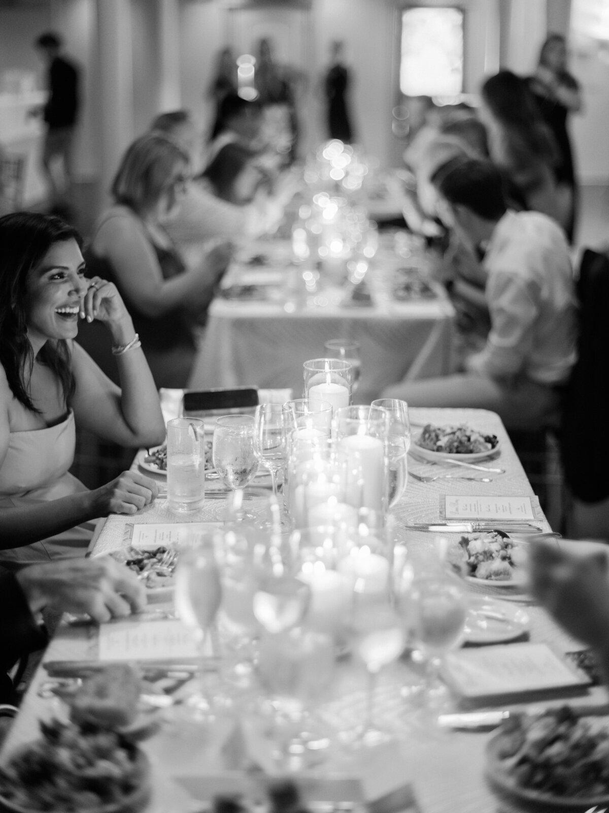 This captivating image shows guests at a dinner table filled with food and candles, sharing laughter and conversation, symbolizing togetherness and warmth in a social atmosphere.