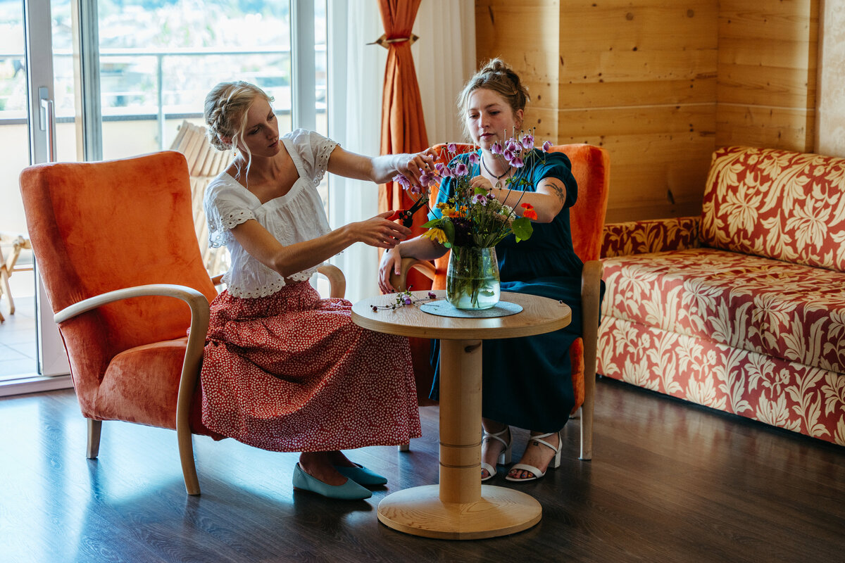 Women arranging flowers together in hotel lounge