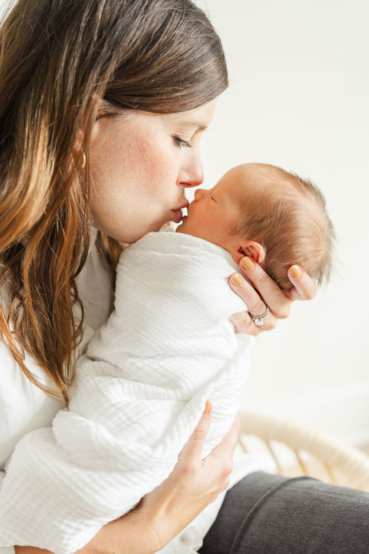 A mother tenderly kissing her swaddled newborn baby, expressing love and affection