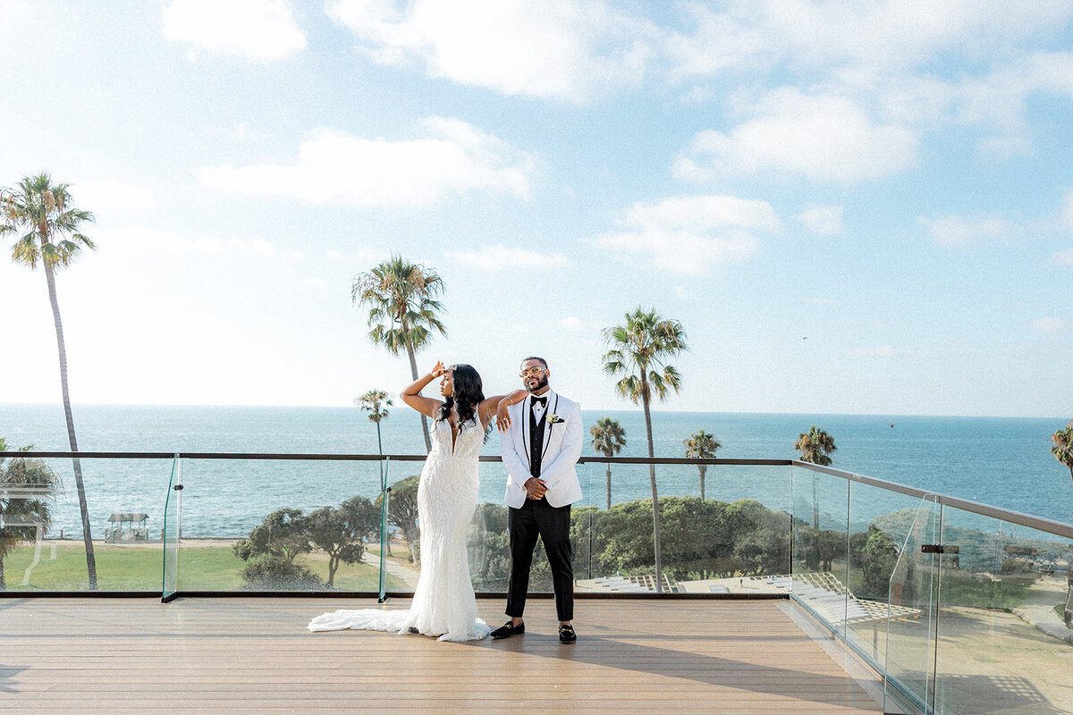 Bride and groom on balcony with the ocean and plam trees behind them in San Diego