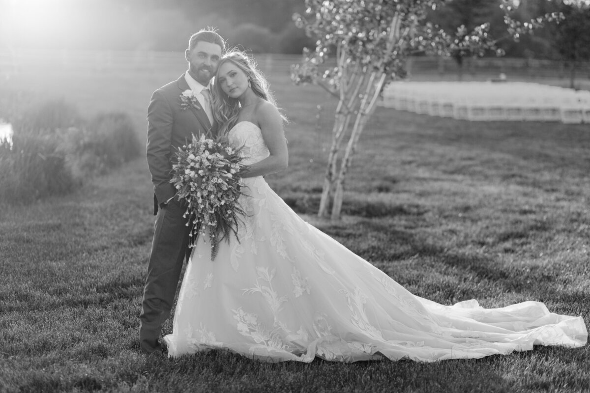 black and white image bride and groom posing in field