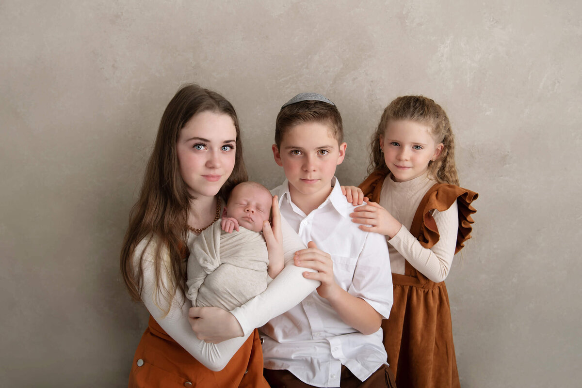 Siblings holding newborn baby sibling for their Burlington newborn photography session.