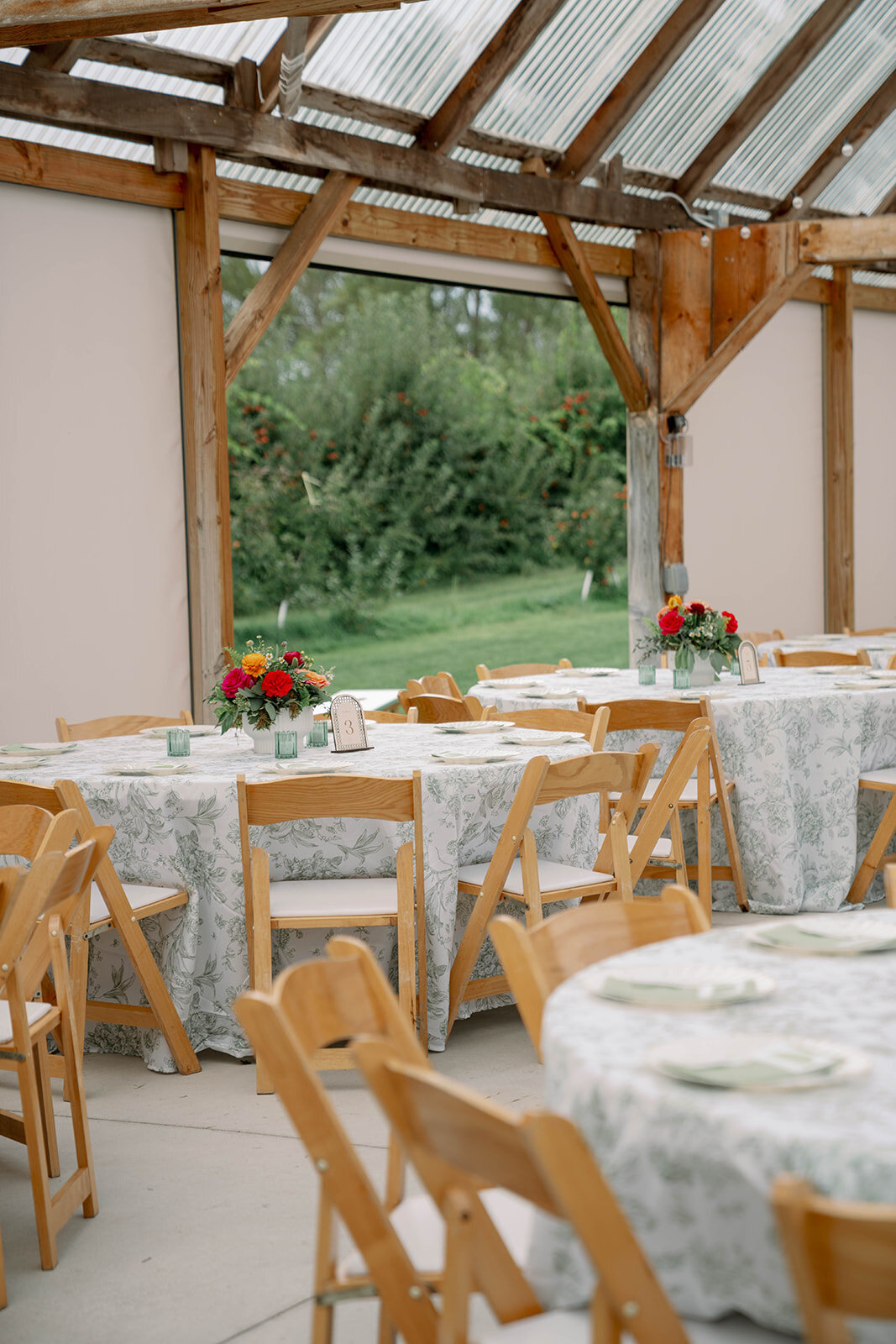 Reception chairs, tables, and full table-scape inside the open-sided outdoor barn at Nugent Orchards in Frankfort MI, showcasing elegant fall wedding décor.