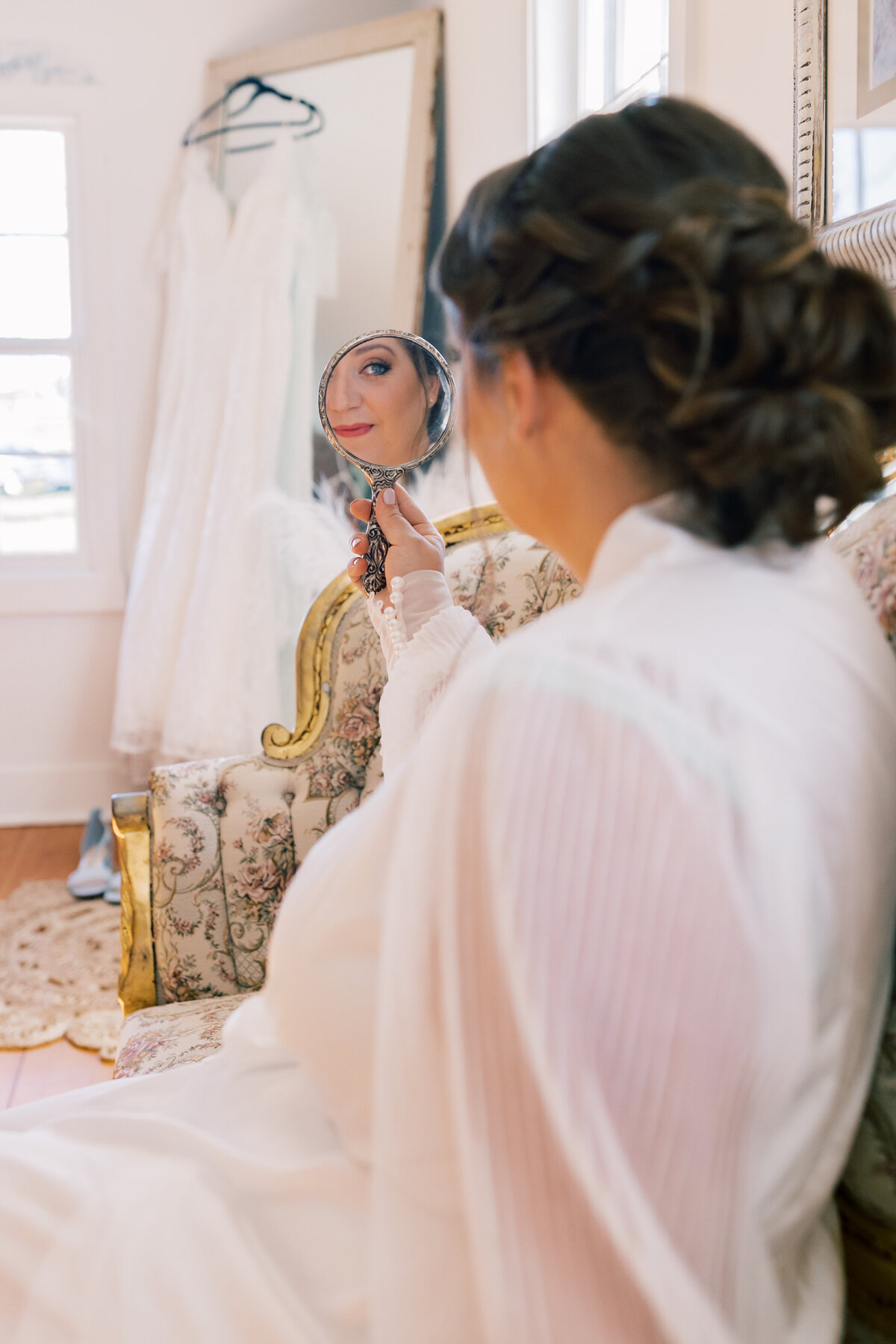 Bride in lace robe smiling at her mother while preparing for her wedding day at The Hummingbird Chateau bridal suite.