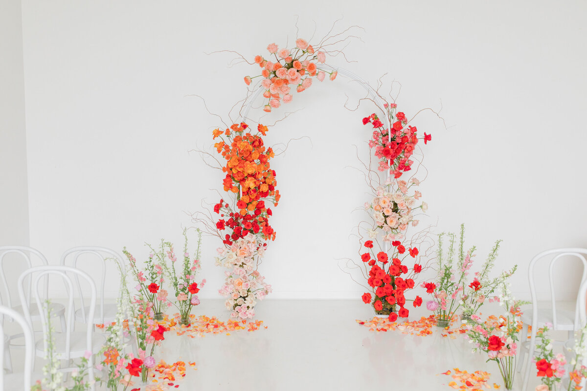 floral arch with bright red , orange and pink florals