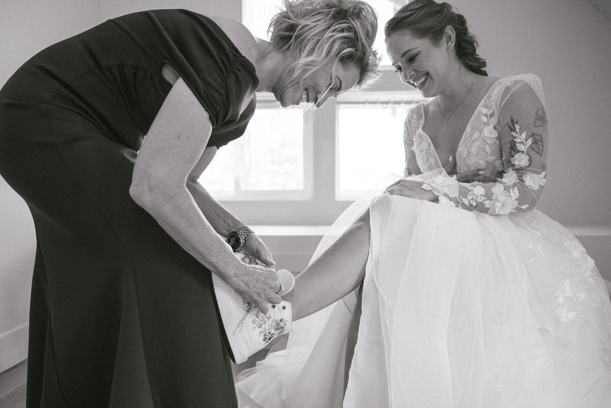 Mother of the bride putting shoes on bride