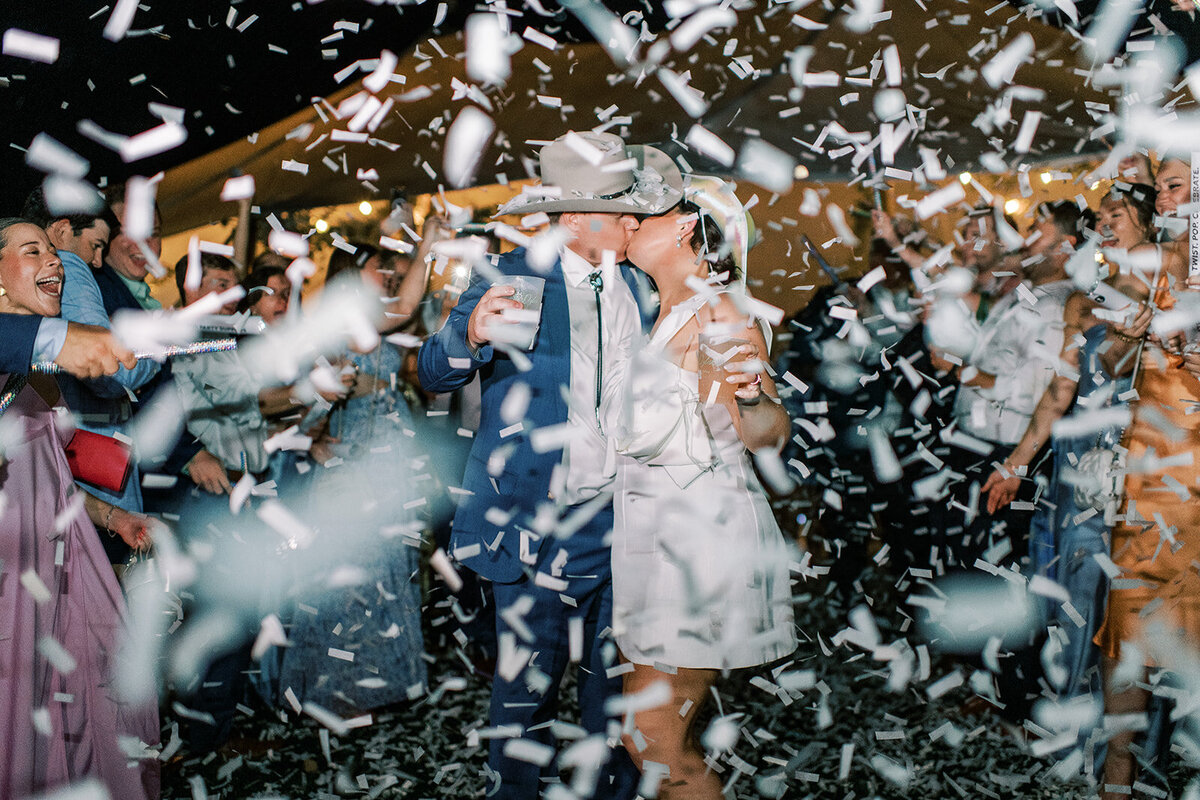 Bride and groom walk through a confetti exit at the end of their sailcloth tent wedding reception in Cashiers, North Carolina.