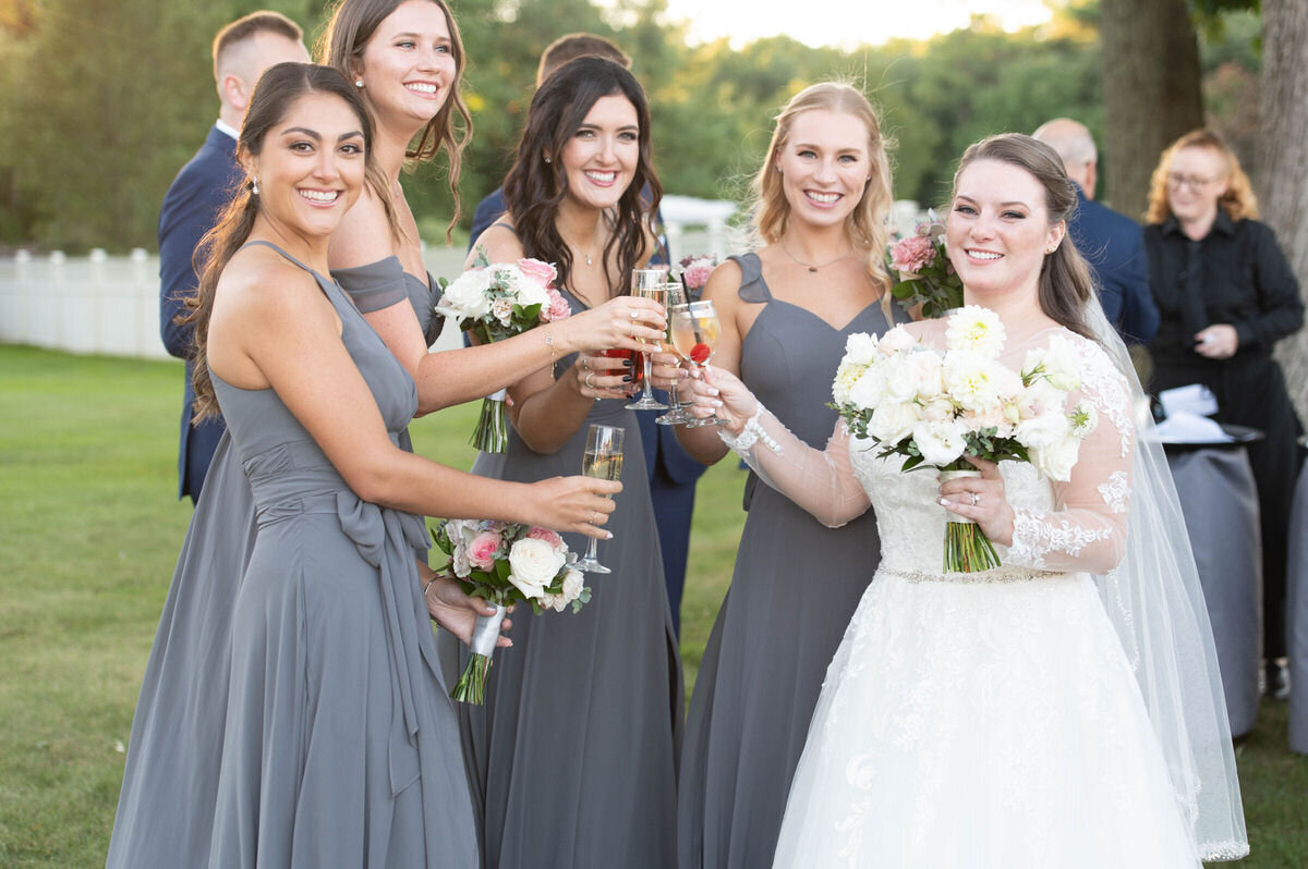 A bride toasting with her bridesmaids with other guests in the background.