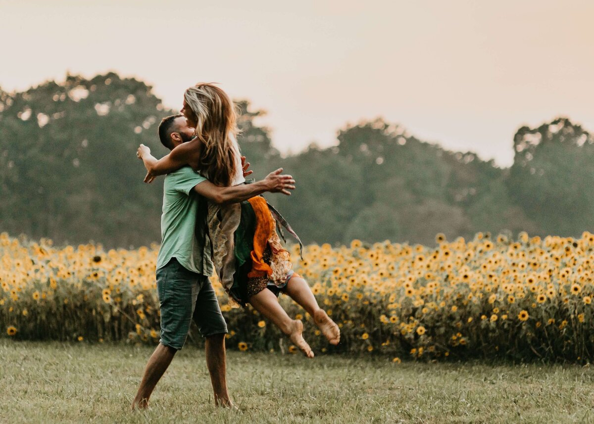 A man and woman embracing in a sunflower field, captured by a Pittsburgh family photographer.