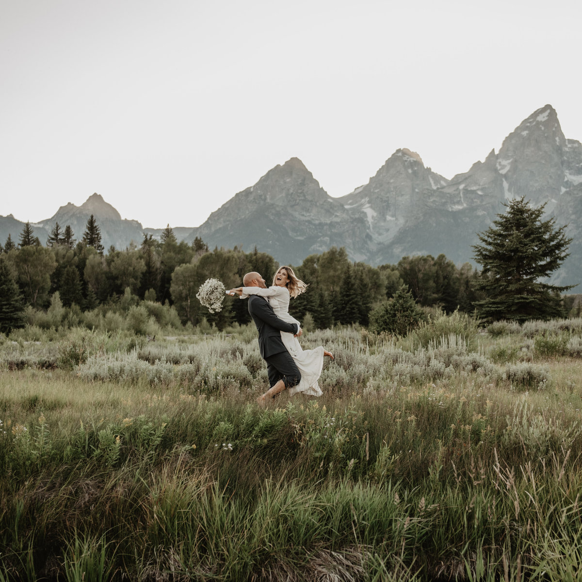 Teton elopement, groom picking up bride and twirling her in a field in front of the Tetons on their wedding day