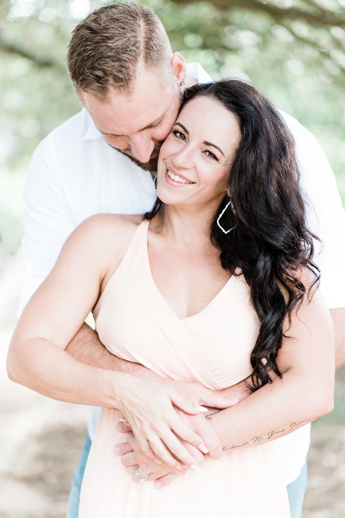 Beautiful engaged woman smiling while fiancé hugs her