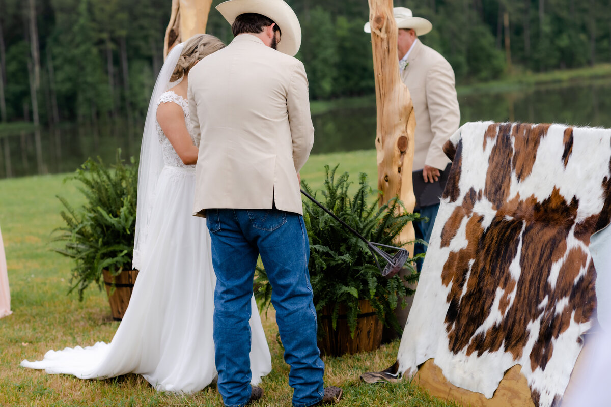 outdoor little rock wedding ceremony with bride and groom branding a cow hyde