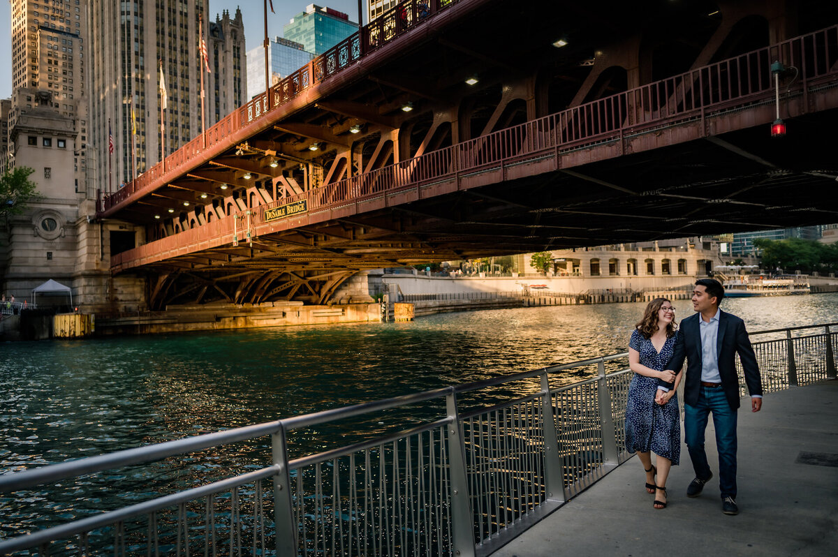 A couple walks under a bridge on the Chicago Riverwalk