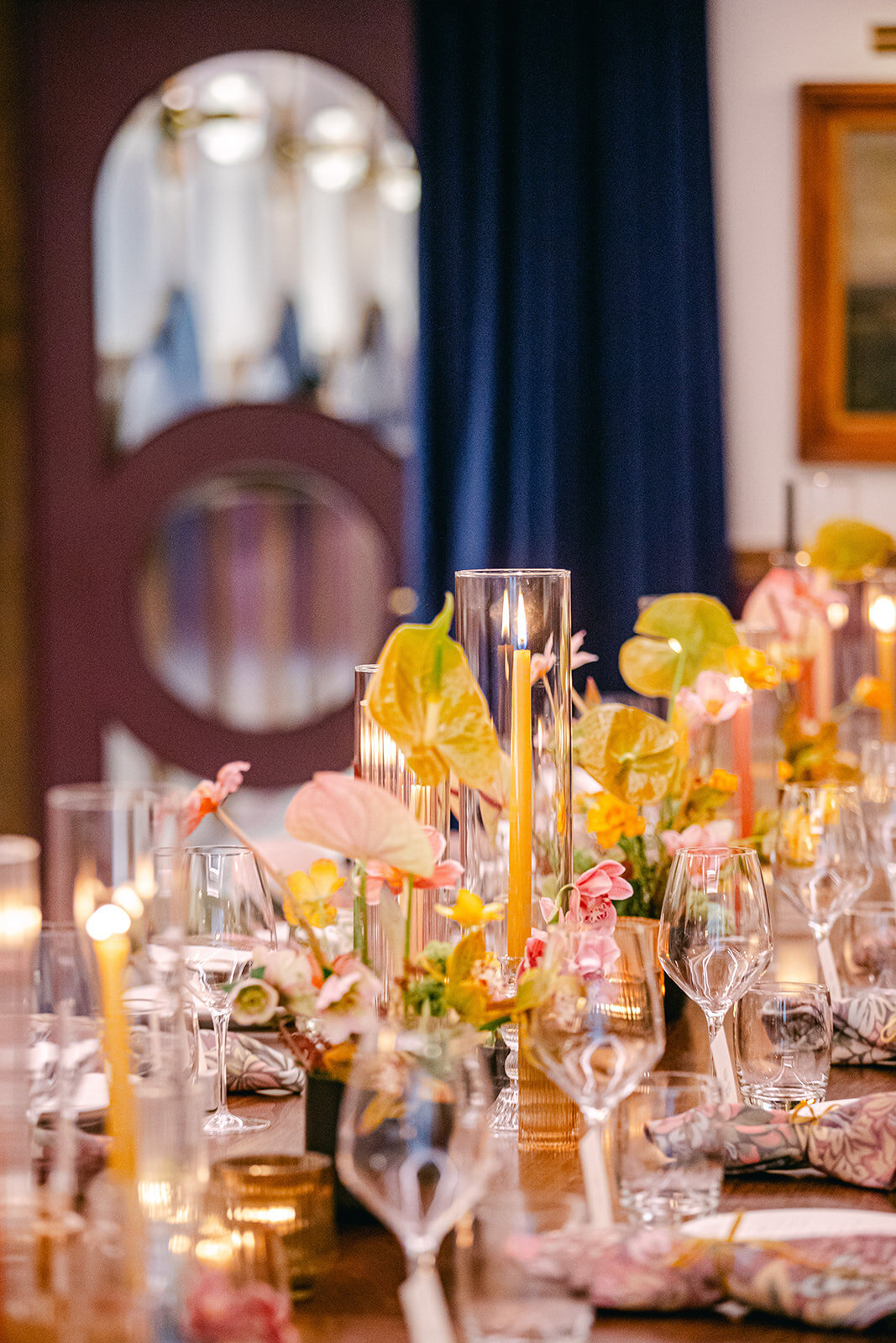 Close-up of a luxurious tablescape with soft candlelight, moody florals, and intricate tableware details