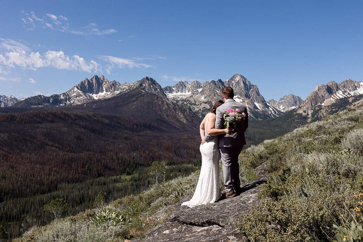 Bride and groom facing each other kissing on a motorcycle.