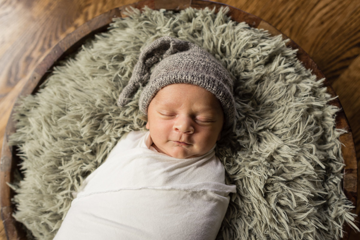 Los Angles Newborn Picture of baby in a cream wrap and green fluff in bowl