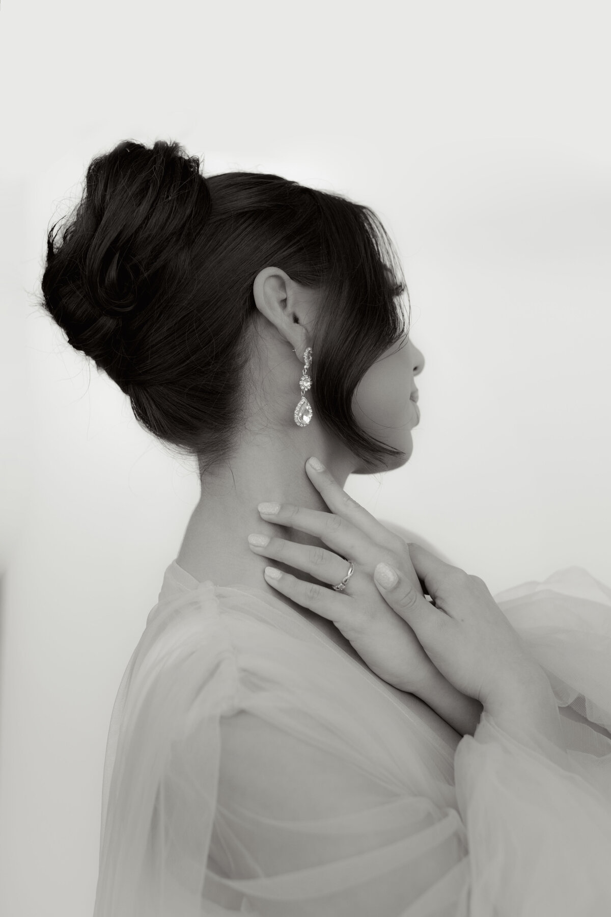 Graceful bridal portrait in black and white featuring a woman in tulle with her hair in a soft updo and diamond drop earrings — romantic, minimal, and editorial.