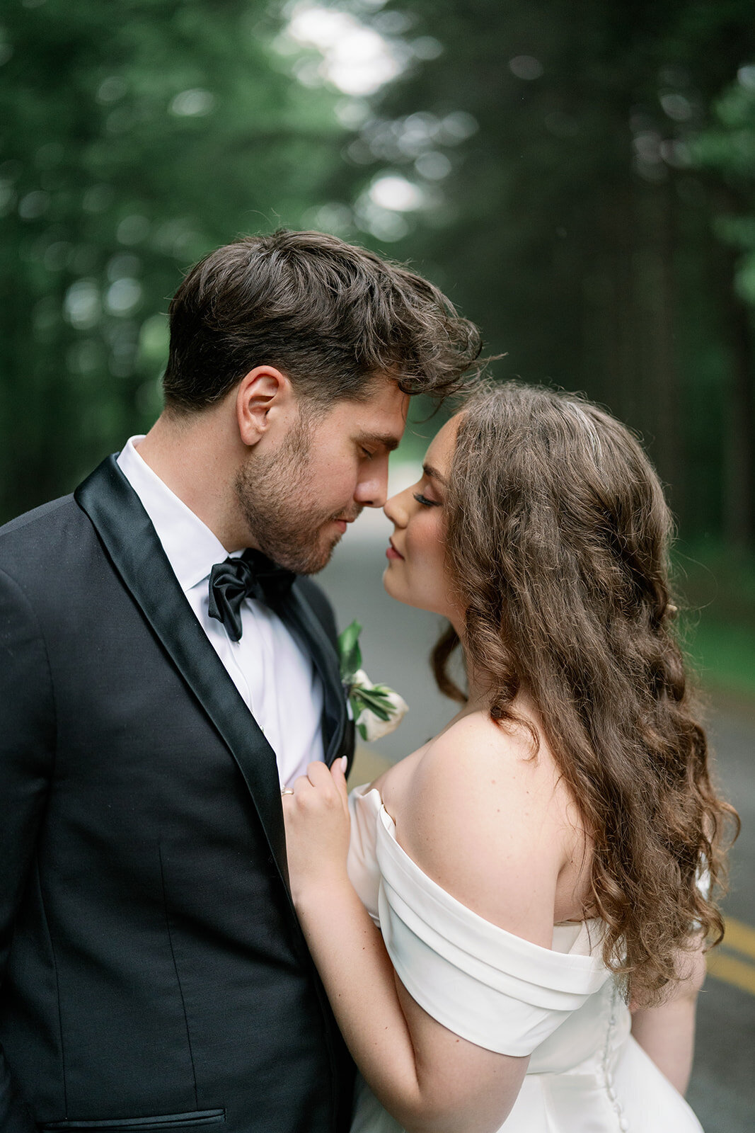 Bride and groom sharing a candid moment in the forest near The Morris Estate wedding venue.