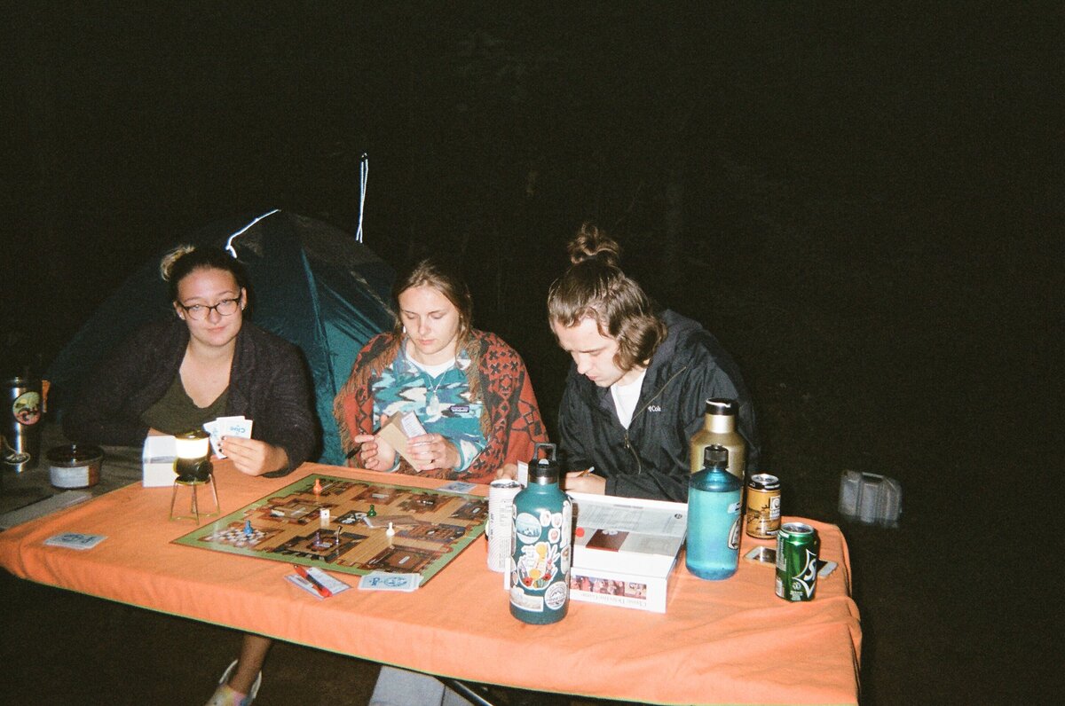 three friends around the picnic table at night playing games