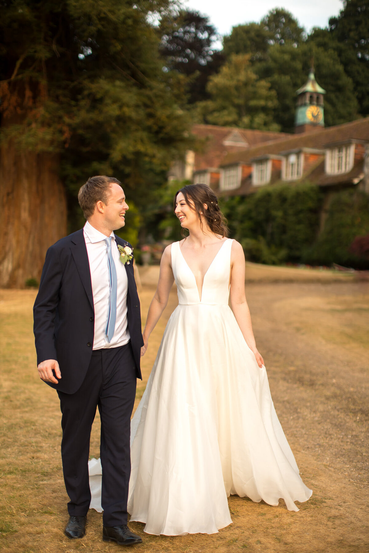 Bride in flowing gown walking with groom at dusk