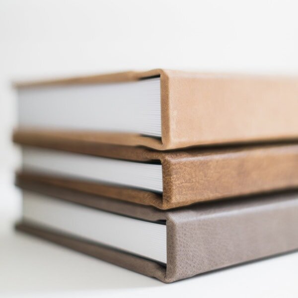 three leather wedding albums stacked on top of each other