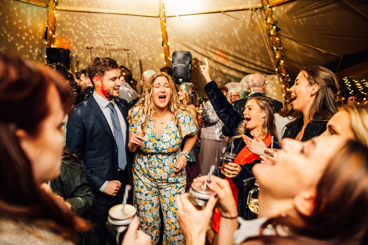 Wedding guests singing and dancing in a circle under reception tent