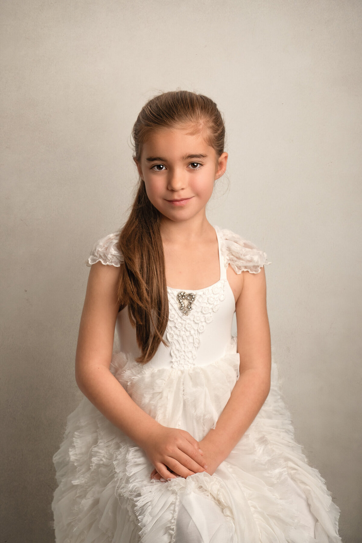 6 year old girl in a pretty white dress with long brown hair smiling at the camera