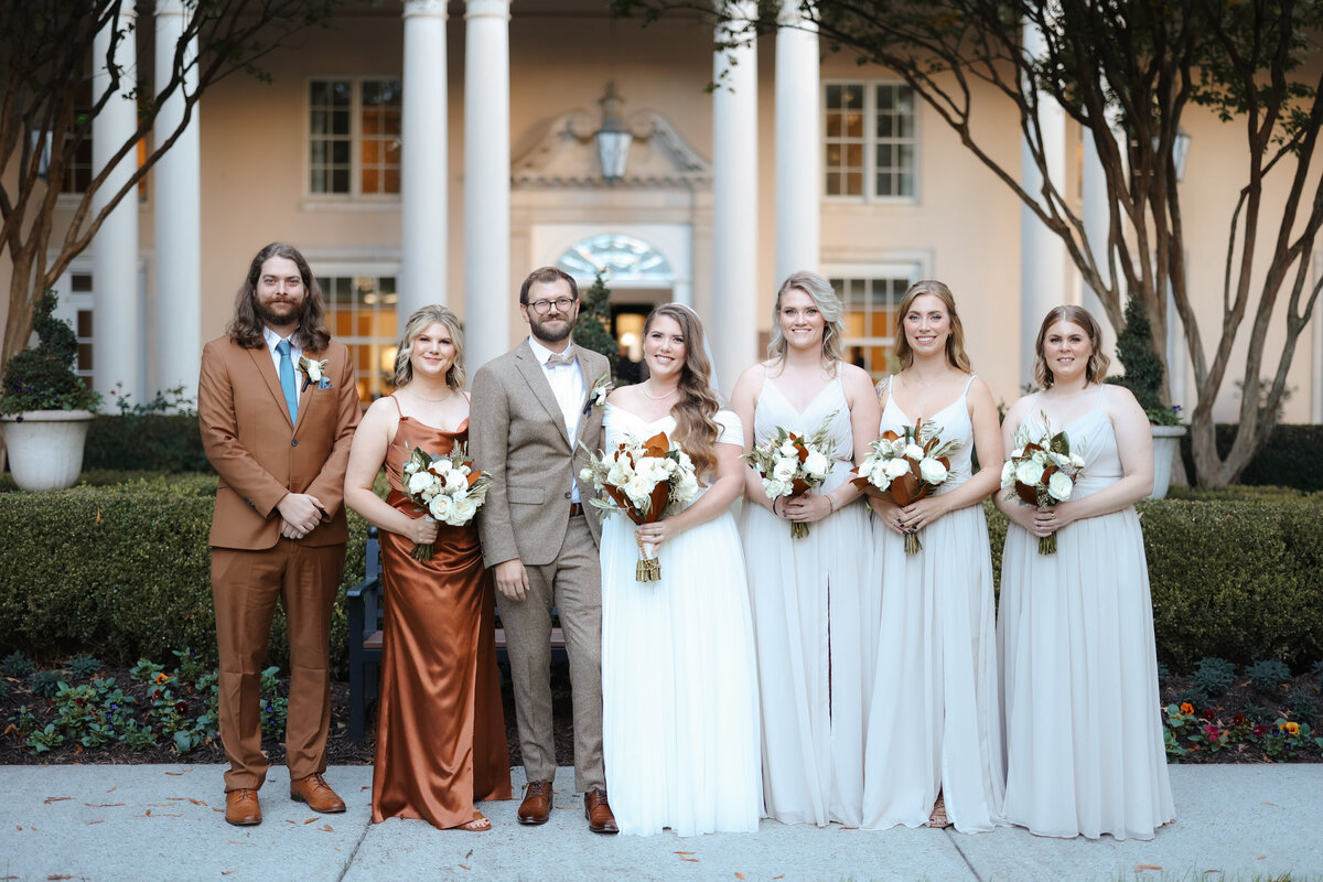 Wedding party standing in front of a natural green backdrop.