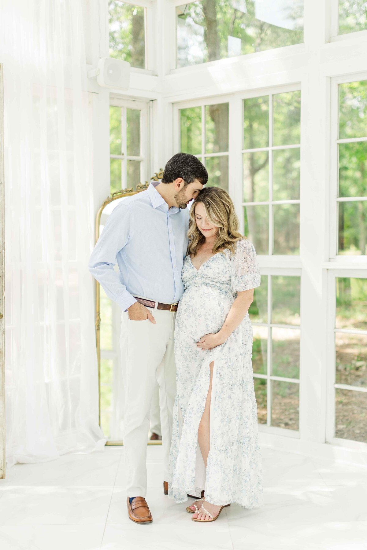 mom and dad embrace in front of glass mirror in conroe studio