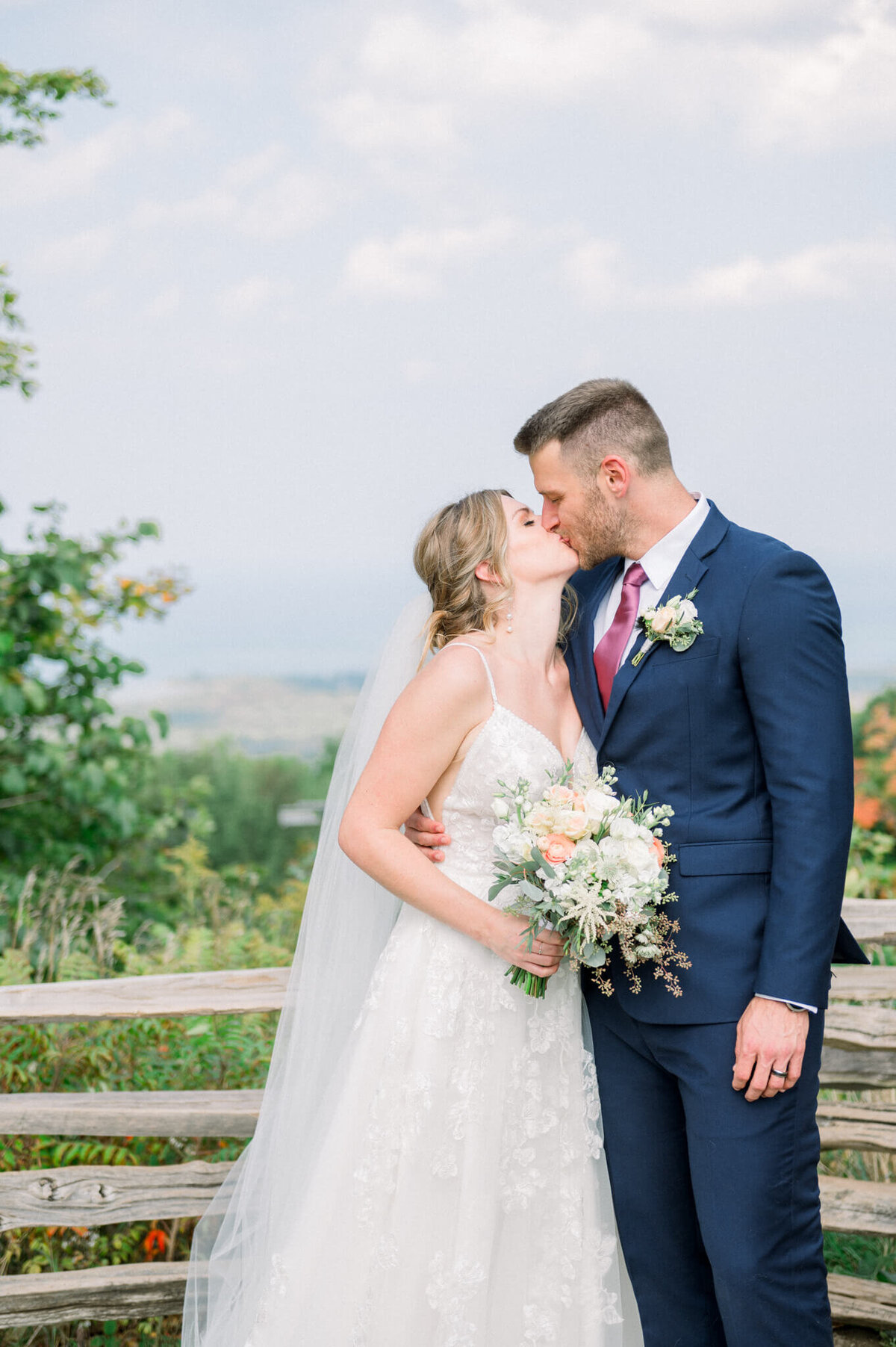 Bride and groom kissing in Blue Mountain for their wedding portrait captured by Niagara wedding photographer