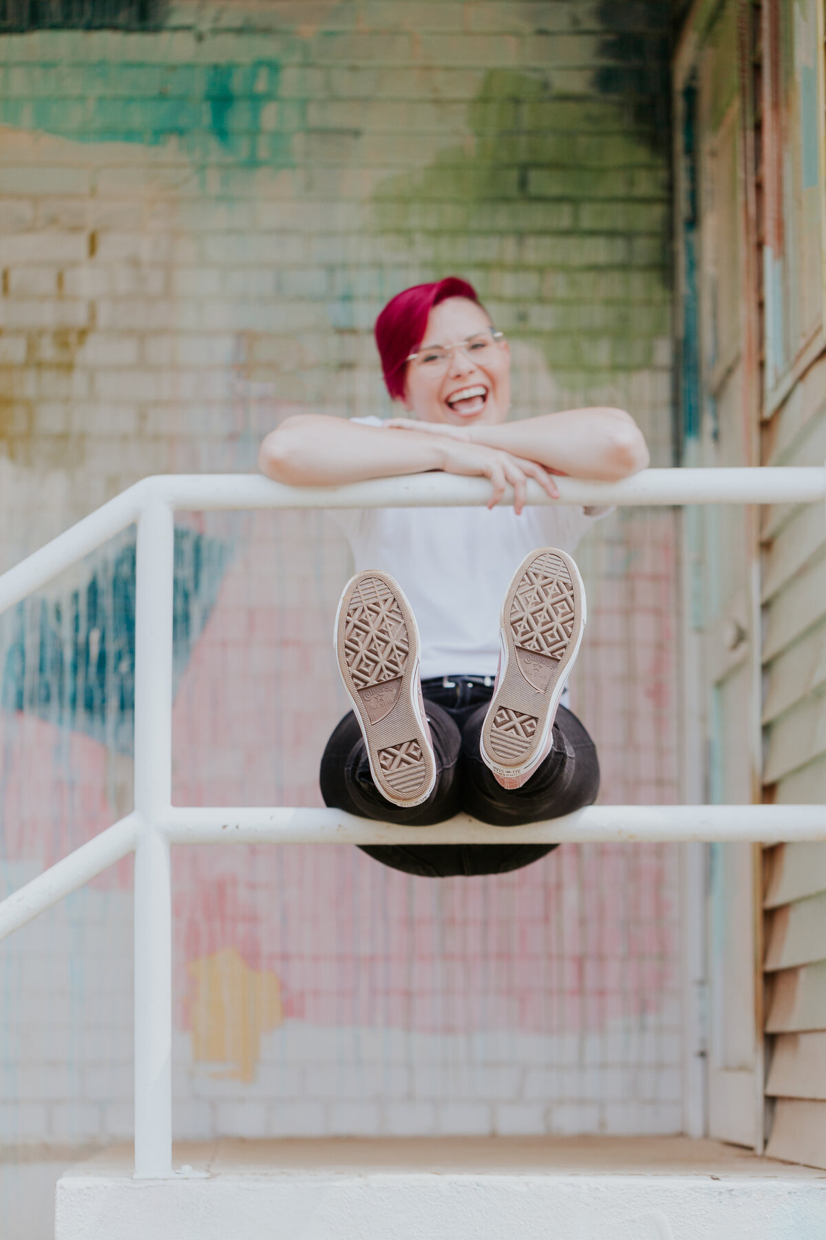 playful-photo-woman-sitting-on-railing-colorful-backdrop-for-brand-session-camp-north-end-charlotte