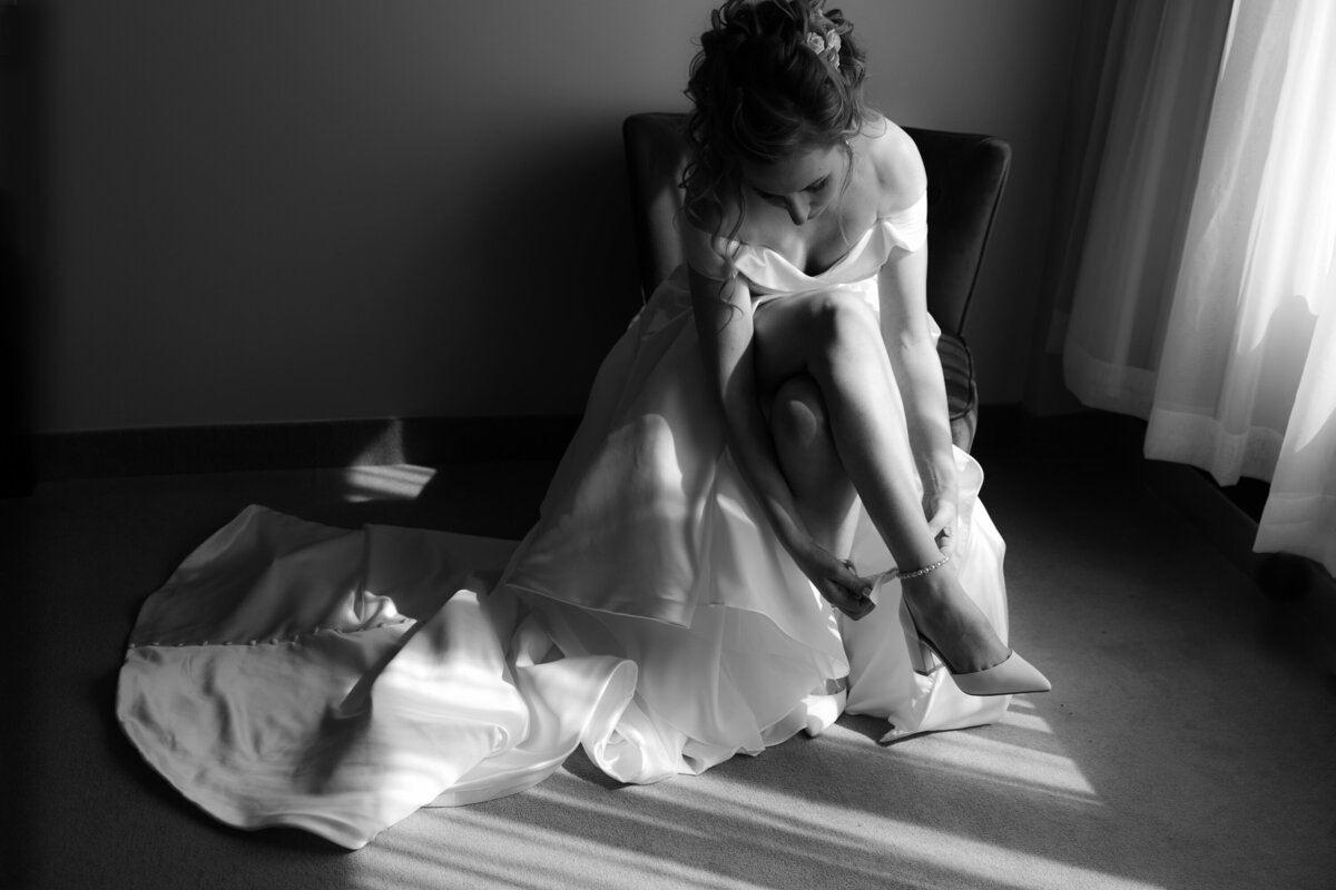 Mariée fixant ses souliers Photo mariage noir et blanc Lumière naturelle
