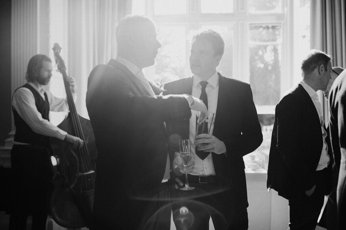 Black and white photo of men talking at intimate wedding
