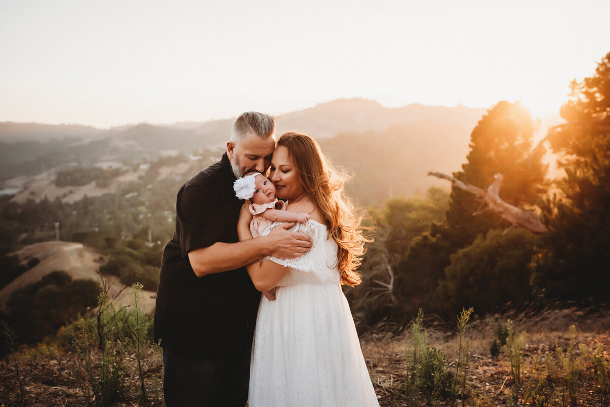 Mother and Father embracing their newborn daughter in the Orinda Hillside