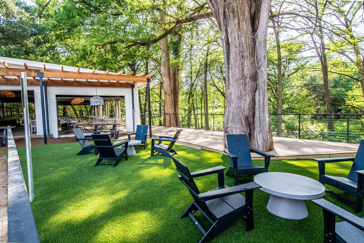 Exterior of creekhouse bar with large trees and exterior tables