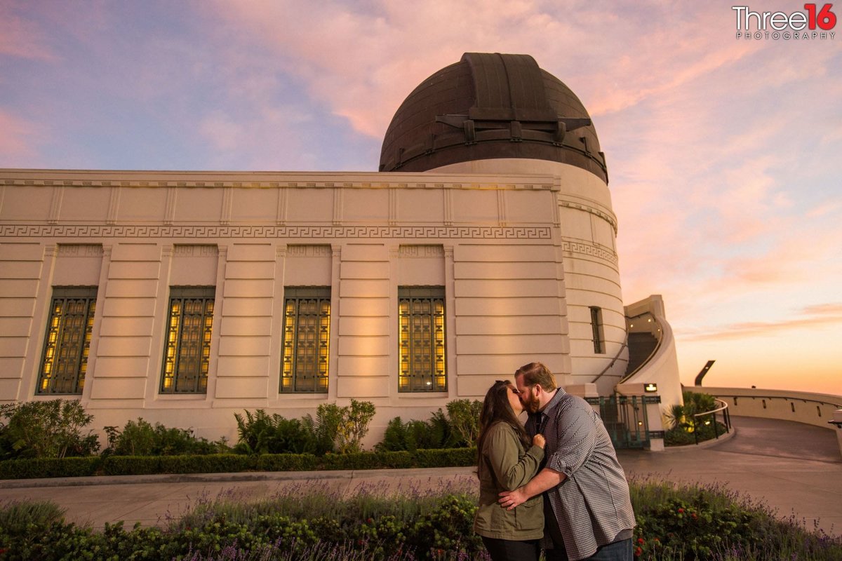 Engaged couple share a kiss in front of the Griffith Observatory
