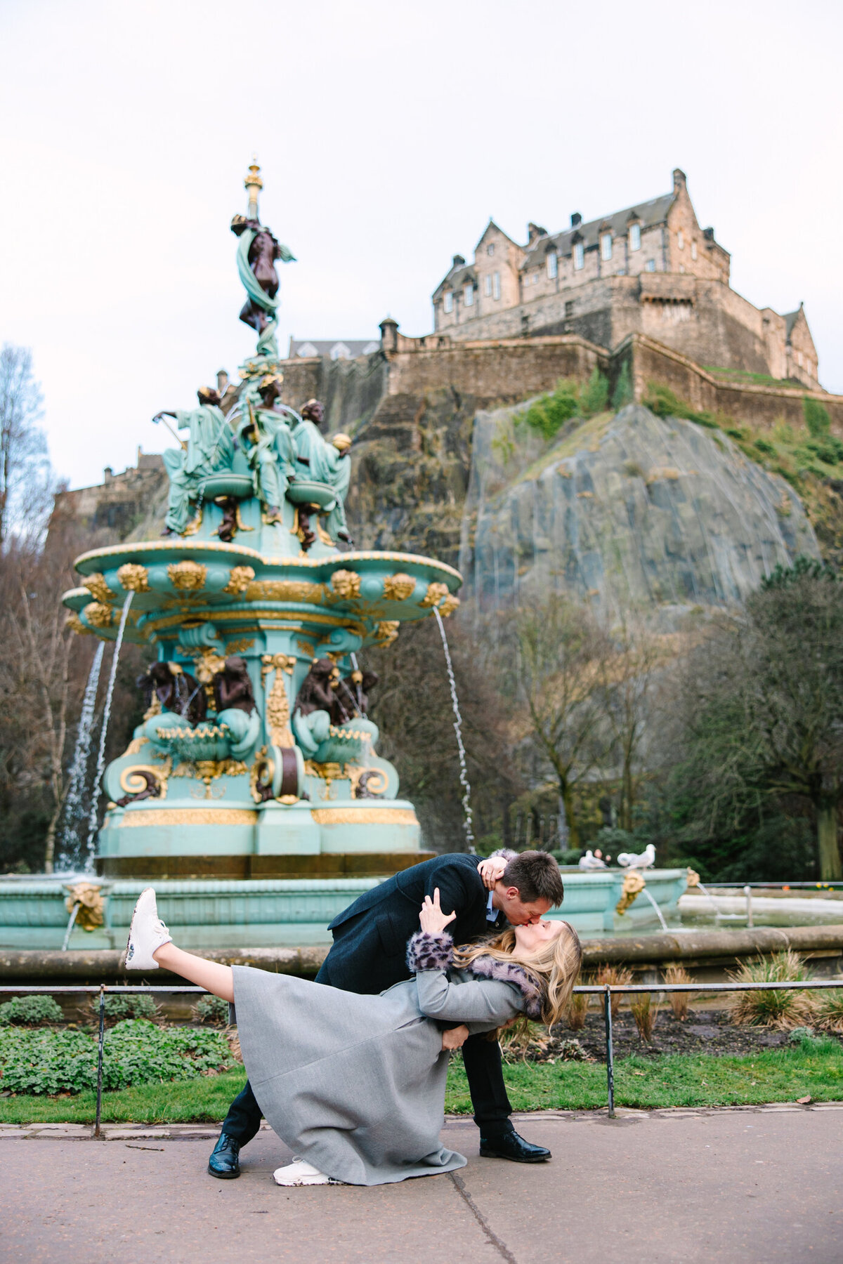 Engaged couple dip and kiss below Edinburgh Castle, photo by Love is Magic Photo