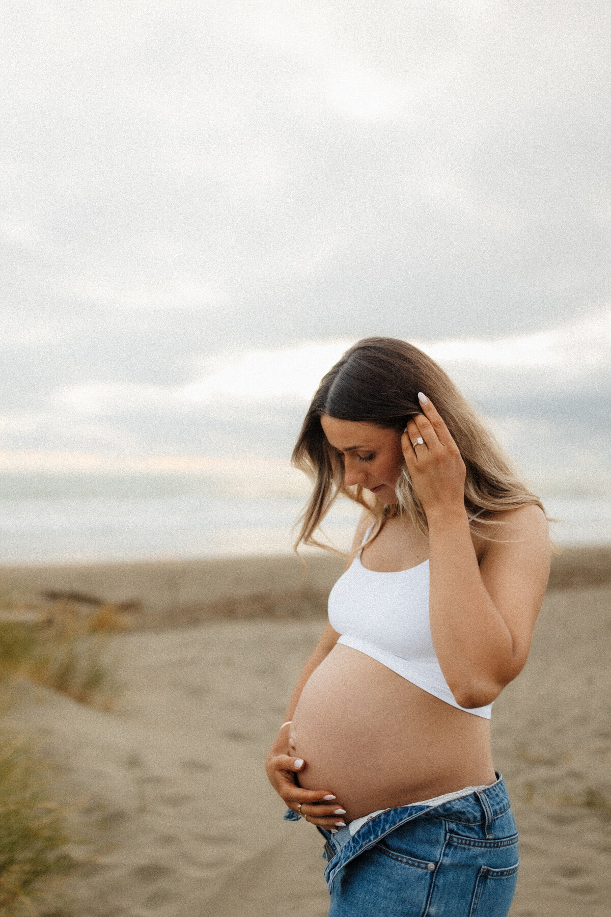 a pregnant mother holds her hair back and holds her belly during a maternity photoshoot with christchurch photographer lucy jane photography