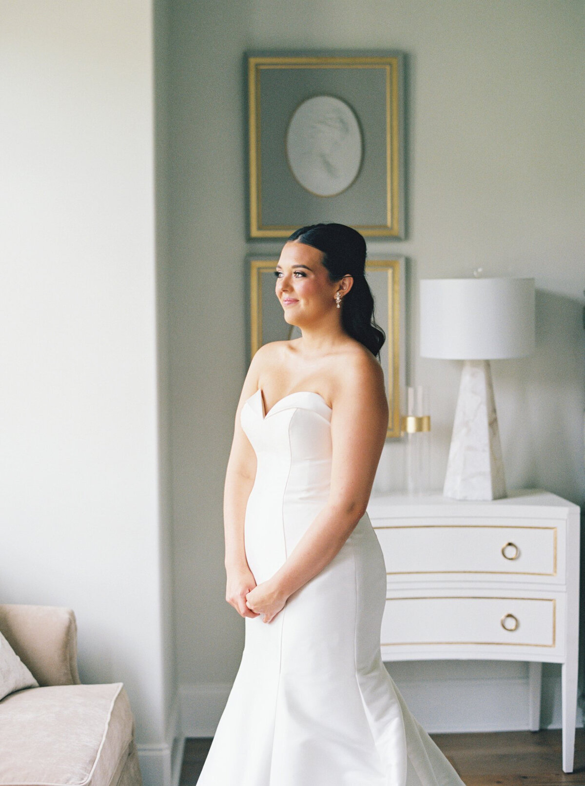 Bride standing elegantly next to a window in a blue and white room, captured on film by Morgan Alysse, Louisiana film photographer.